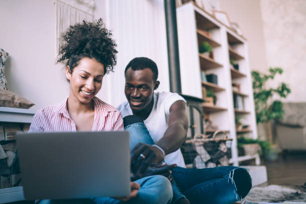 istock Multiethnic couple in casual clothes using laptop sitting on floor 1452928956