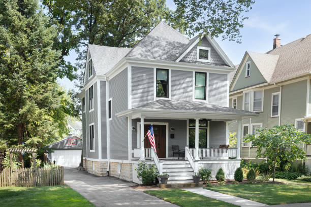 A grey and white Victorian home. Chicago, IL, USA - August 1, 2020: A beautifully renovated Victorian home with a grey and white siding, a covered front porch and a driveway leading to the backyard. victorian houses exterior stock pictures, royalty-free photos & images