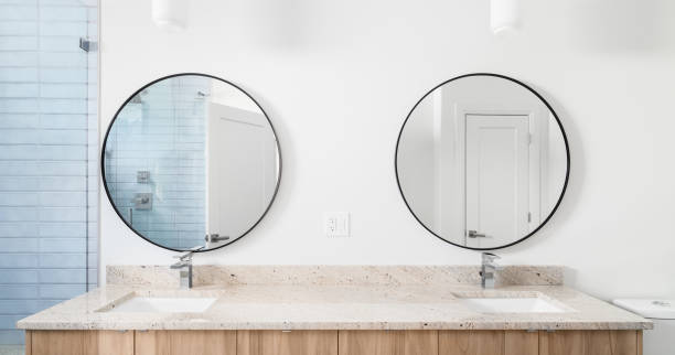 A bathroom with a wood cabinet and circular mirrors.