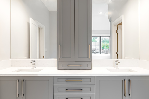 A gray vanity in a large luxurious bathroom with granite counter tops and chrome fixtures.