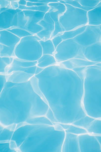 Background, blue water waves in the pool with sun reflection. Selective focus