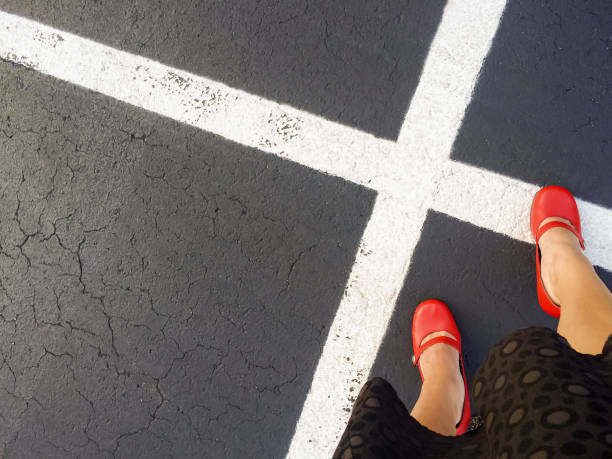 sapatos vermelhos estouram esperando em um estacionamento onde x marca o local - x stand - fotografias e filmes do acervo