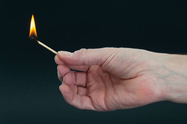 istock Burning matchstick in hand on a dark background 1452933476
