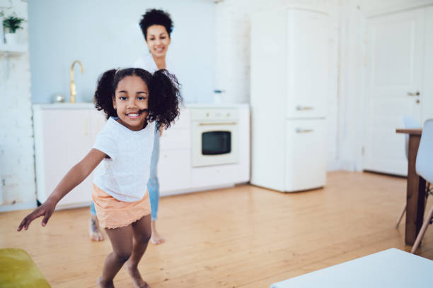 istock Cheerful black girl running and leading mother while looking ta camera 1452939122