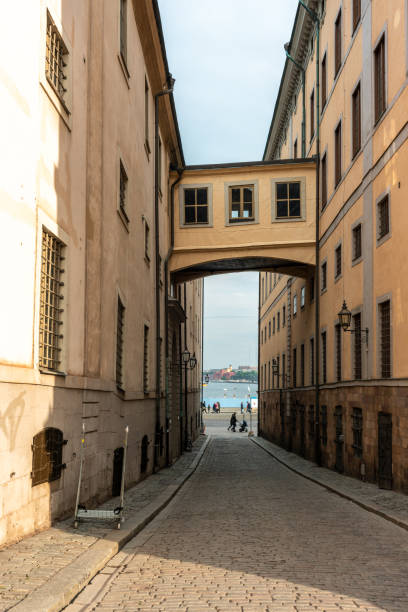 Stockholm, Sweden - September 11, 2021: Architectural view of narrow street with arch bridge between two buildings in The Old Town with incidental people in Stockholm Sweden September 11, 2021.