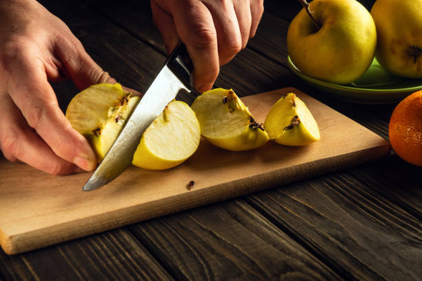 istock Making apple compote or fruit drink at home. Hands of a cook with a knife cutting fresh apples on a cutting board 1452943117