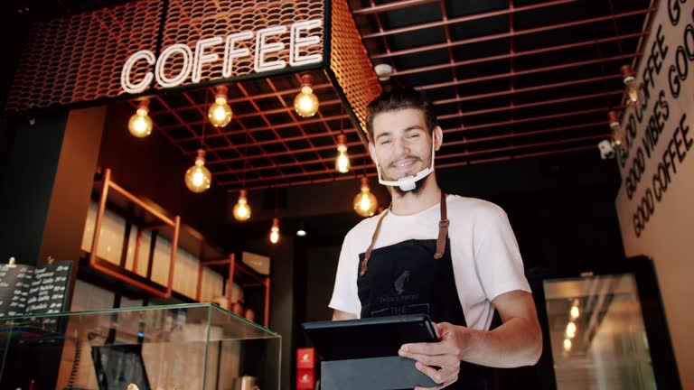 Young waiter browsing tablet during work in cafe