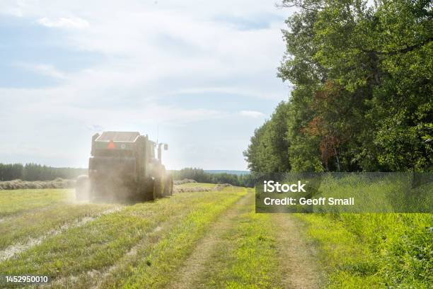 Tractor Pulling A Hay Baler Through A Field Stock Photo - Download Image Now - Agricultural Field, Agricultural Machinery, Agriculture