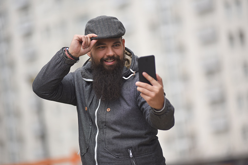 Shot of a young hipster man using a smartphone against an urban background