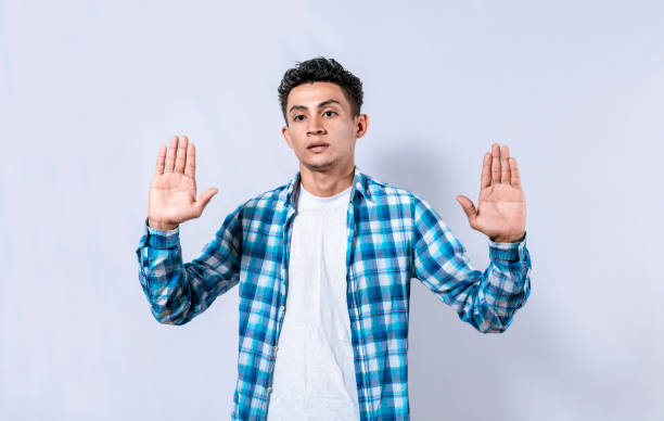 istock Scared and horrified man with raised palms, Man with a frightened face with his hands raised in front. Portrait of scared person with raised hands, Scared guy with raised hands in front 1452961742