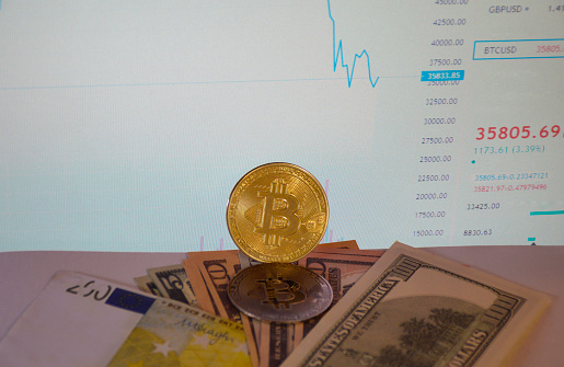 Tiraspol, Moldova - May 30, 2021: two coins bitcoin and dollars on the background of a stock chart bigram. increase in the share of cryptocurrency in the global financial system. rejection of cash, paper money