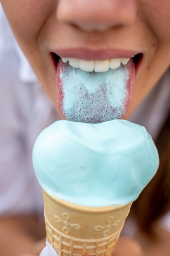 Young woman with a blue tongue licking a new fantasy flavour of blue ice cream