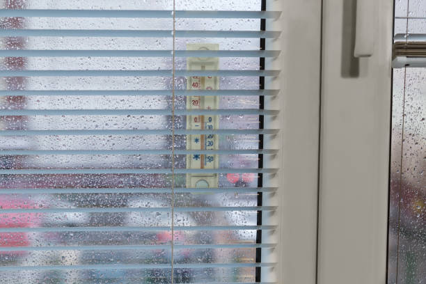 istock Window covered with water drops, attached outdoor thermometer, inside view 1452969475