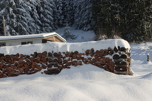 A fresh layer of snow covering the winter pile of firewood