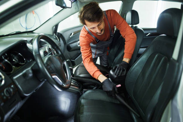 Young handsome man vacuuming car seats