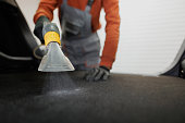 Close up shot of an unrecognizable man cleaning car trunk with a wet-dry vacuum cleaner