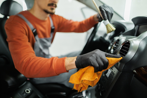 Professional car detailer cleaning car interior with a microfiber towel