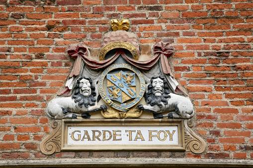 Amsterdam, Netherlands: civic coat of arms of Amsterdam- red shield and a black pale with three silver Saint Andrew's Crosses - shield of Amsterdam on a brick wall.