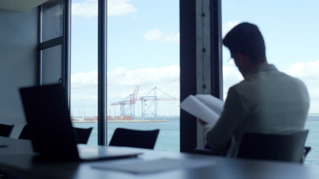 Man expert reading documents at marina seaport view. Manager checking report