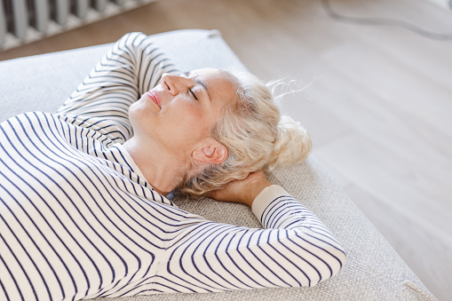 Photo of a mature woman relaxing on the sofa with her eyes closed