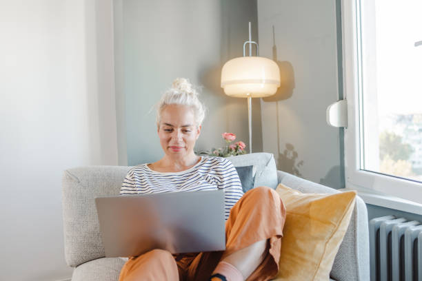 istock Mature woman relaxing on the sofa and using a laptop 1452979891
