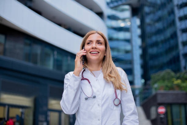 Mature Male Doctor Sitting In Clinic And Talking On Telephone