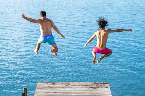 istock Two men enjoying their holiday while jumping into the lake from the pier 1452986609