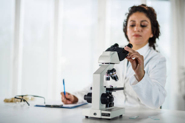 istock Female scientist writing the results of analyzed samples after examining them under a microscope 1452986872