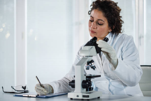 istock Female scientist writing the results of analyzed samples after examining them under a microscope 1452986877