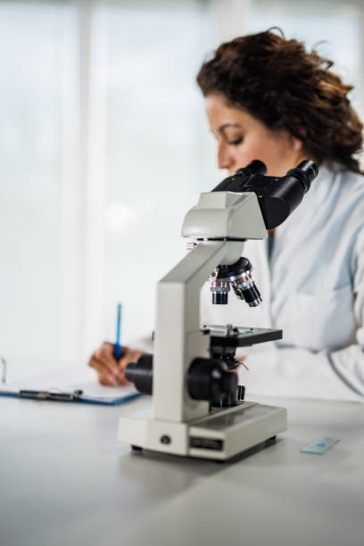 istock Lab tech writing her findings on a clipboard after looking through the microscope and analyzing samples 1452986880