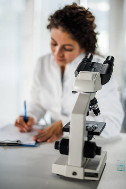 istock Lab tech writing her findings on a clipboard after looking through the microscope and analyzing samples 1452986888
