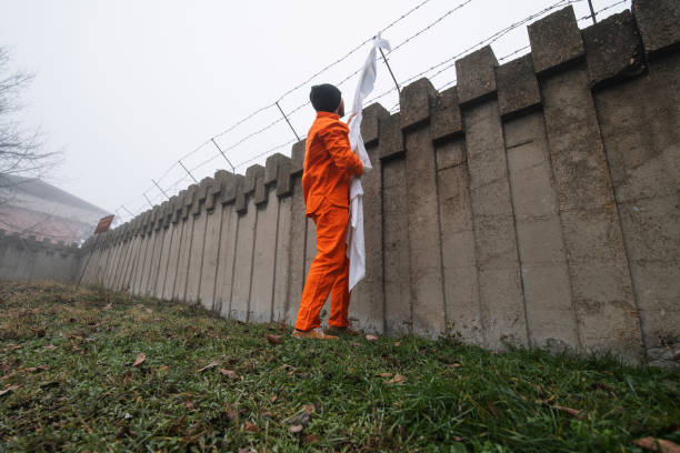 A fugitive using sheet to escape prison. A fugitive wearing orange bodysuit using sheet to escape prison. prison escape stock pictures, royalty-free photos & images