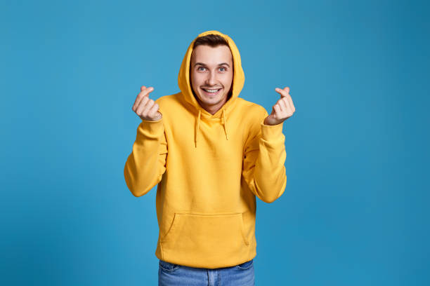 istock young man in yellow sweatshirt showing love gesture 1452987839