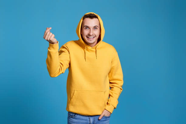 istock young man in yellow sweatshirt showing love gesture 1452987844