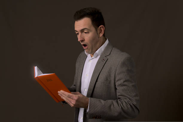 istock Overwhelmed Professional officeholder reads 2023 objective orange notebook. Concept stress in office worker people 1452990198