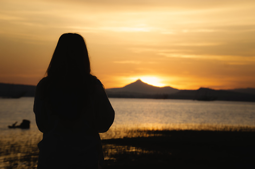 Silhouette back views of a free woman enjoying the freedom and feeling happy at sunrice. Serene relaxing woman in pure happiness nature lake view.