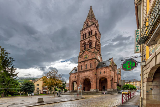 the red brick protestant church in the main town square of the city of munster, france, in the alsace region, under cloudy stormy skies in late summer. - haut rhin imagens e fotografias de stock