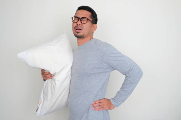 istock Adult Asian man hugging sleeping pillow while touching his back with in pain expression 1452996536