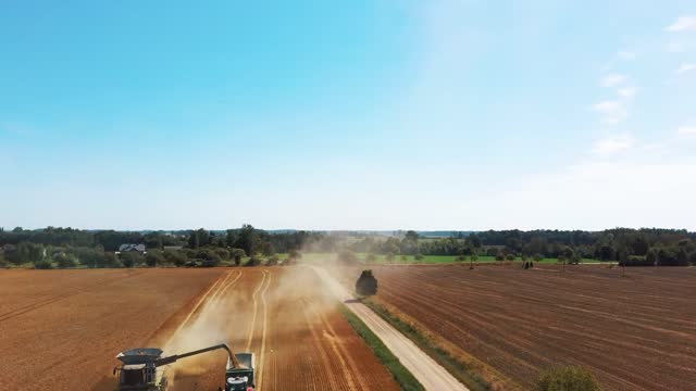 Aerial Shot of Combine Loading Off Corn Grains Into Tractor Trailer. Agricultural Machines Working in Farmland During Harvesting. Farming Concept. Top View