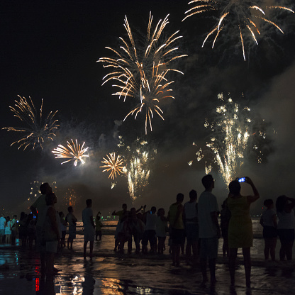 Santos city, Brazil.  New Year's celebration on the beach. People watching the fireworks at the water's edge.
