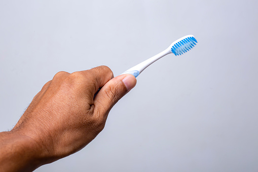 Hand holding toothbrush isolated on gray background . Toothbrush concept.