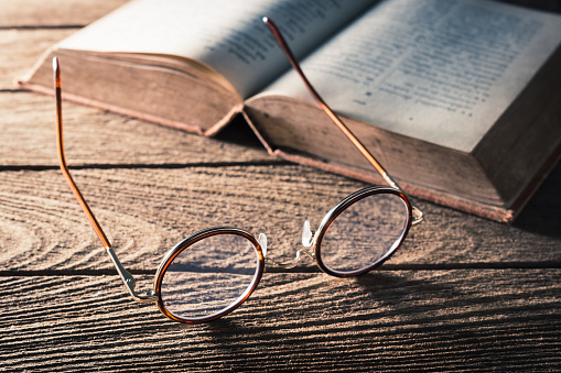 vintage eyeglasses and old textbook on old wooden table