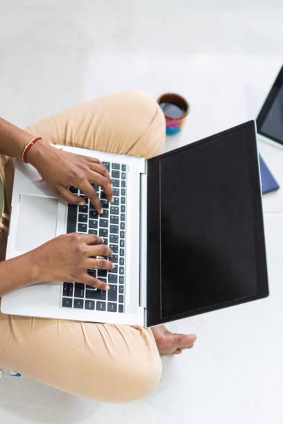 istock Unrecognizable woman working at home with a laptop on a floor. Writing an email. 1453002455