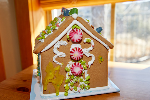 Close up of homemade colourful gingerbread house with candy cane tree