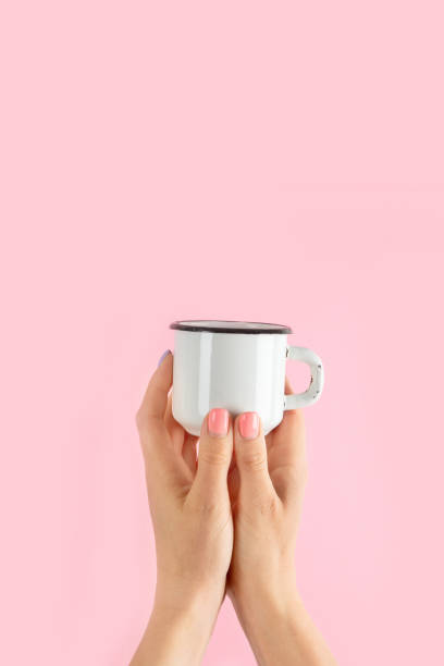 istock Arms raised up holding coffee cup on pink background. 1453025093