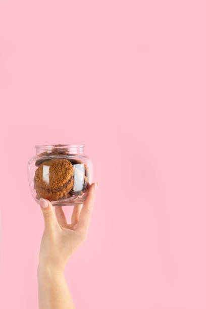 istock Arms raised up holding coffee cup on pink background. 1453025110
