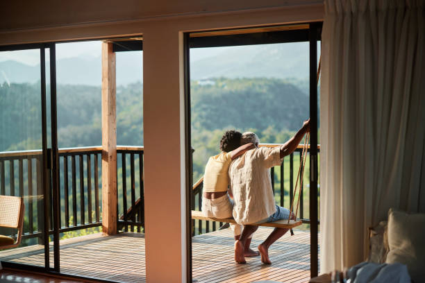 istock Affectionate couple sitting on a balcony swing and looking at the scenic view 1453027153