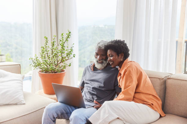 istock Smiling couple using a laptop in their living room with a scenic view 1453028518