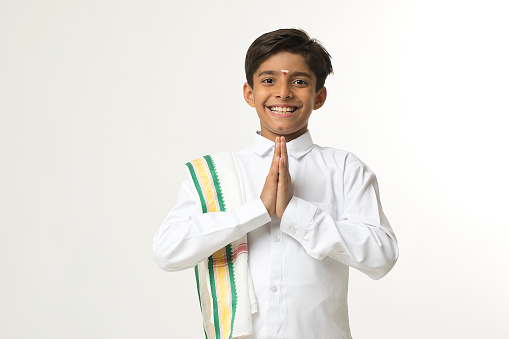 Happy south indian boy in traditional clothing greeting in prayer pose