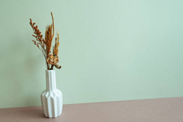 istock Vase of brown dry flowers on table. mint wall background. home interior, copy space 1453033921